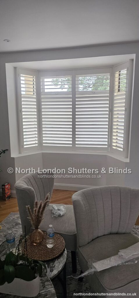 White tier-on-tier plantation shutters on a bay window in a living room by shutter fitters in Barnet, North London