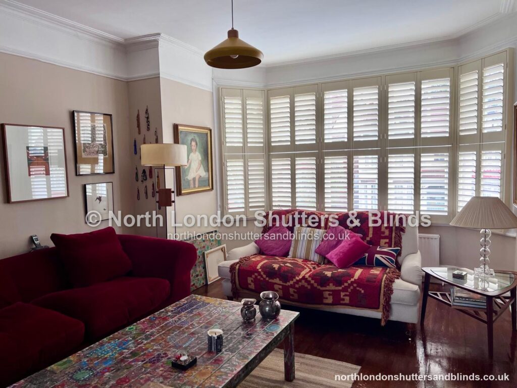 White tier-on-tier plantation shutters on a large bay window in a living room by shutter fitters in Barnet, North London