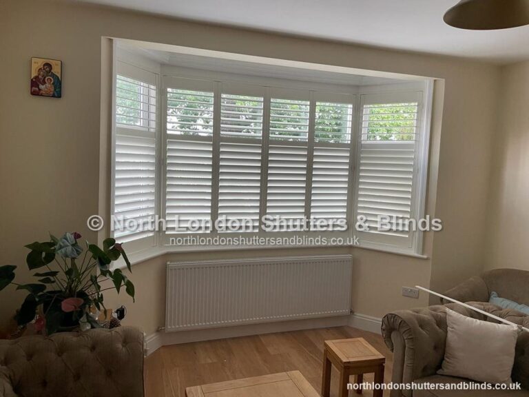White tier-on-tier plantation shutters on a square bay window in a living room by shutter fitters in Barnet, North London