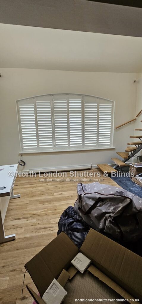White special shape plantation shutters on an arched window in a loft room by shutter fitters in Barnet, North London